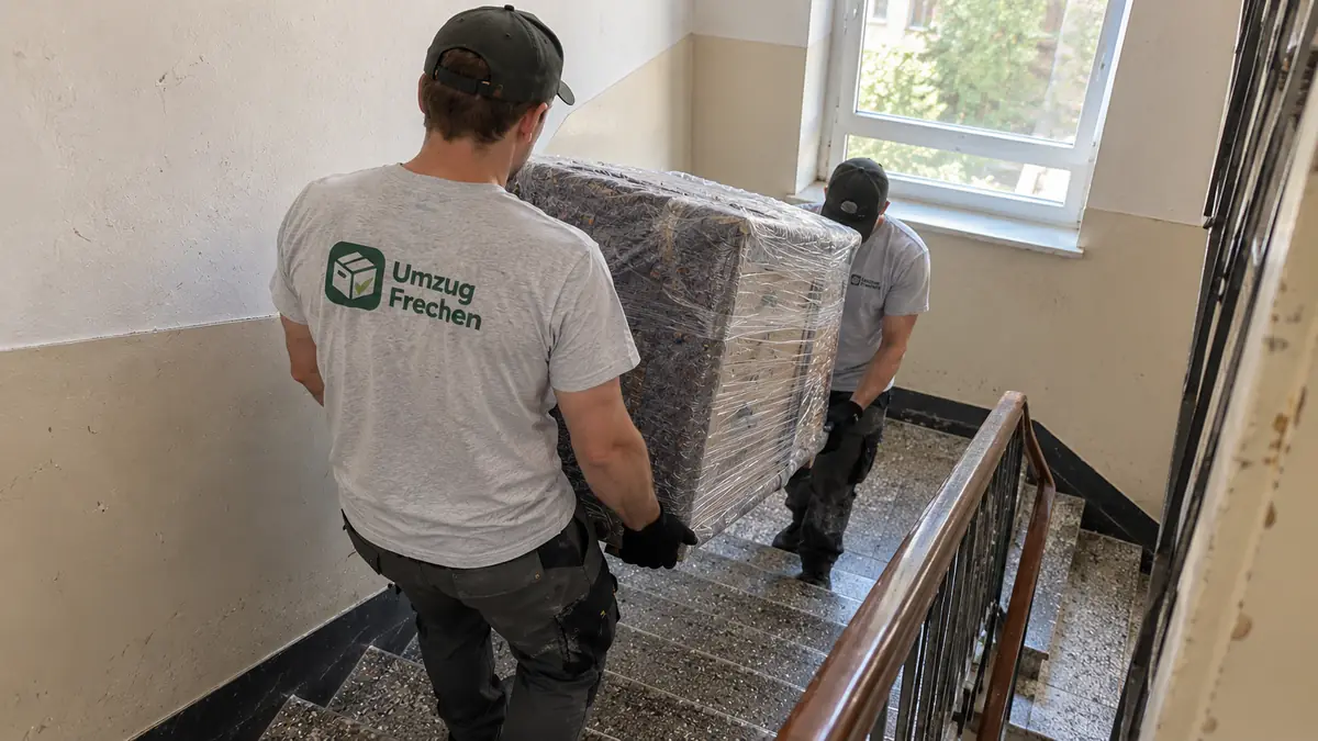 Privatumzug Frechen: zwei Umzugshelfer tragen eine Kommode die Treppe hinunter